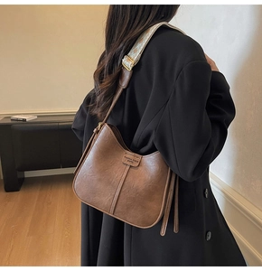Détail d'un sac hobo marron avec bandoulière en jacquard large et boucles dorées