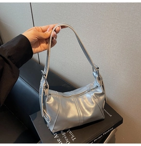 Detail of silver metallic hobo bag featuring a star zipper pull and vertical stitching