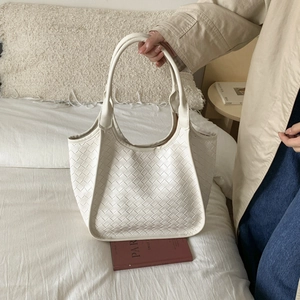 Detail of white woven leather tote bag with classic intrecciato weave and dual handles