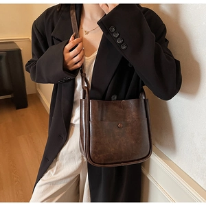 Detail of vintage brown crossbody bucket bag featuring adjustable strap and snap pocket