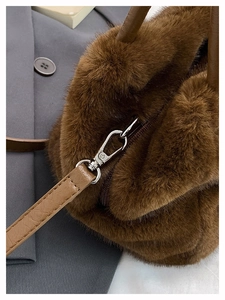 Detail einer braunen Kunstpelz-Handtasche mit Kunstledergriff und silberner Schnalle