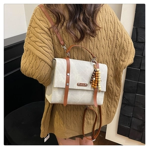 Détail du sac à dos vintage en cuir gris avec perles en bois et touches de cuir marron