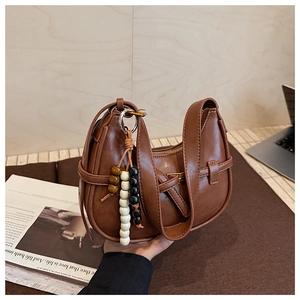 Detail of vintage brown leather dumpling bag with wood bead tassel and neat stitching