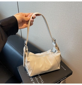 Detail of hobo bag in cream faux leather with silver buckle and star pendant accessory