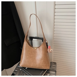 Brown leather tote bag featuring a gold metal bar closure and cute plush animal charm