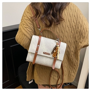 Détails du sac bandoulière beige avec lanières en cuir marron et perles en bois décoratives