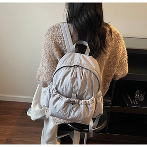 Close-up of lightweight light gray nylon backpack with drawstring pocket and zipper
