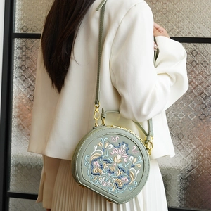 Detail of grey-green crossbody bag with traditional Chinese floral embroidery and gold hardware
