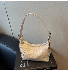 Detail of beige patent leather shoulder bag with glossy finish and silver metal hardware