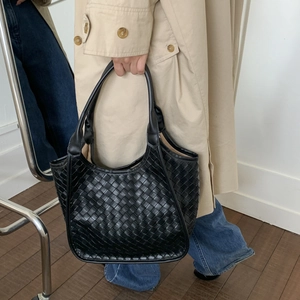 Close-up of a black hand-woven tote bag showing detailed Intrecciato leather texture