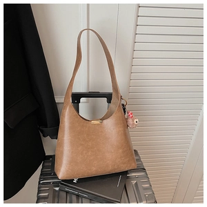 Detail of vintage brown bucket bag with plush bear charm on a metal suitcase