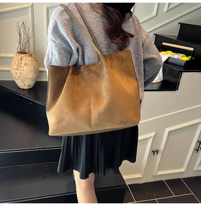 Detailed view of the large brown suede tote bag worn on shoulder by a model