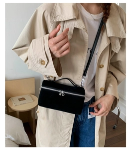 Detail einer matten schwarzen Box-Tasche mit Griff und schlankem Leder-Schultergurt