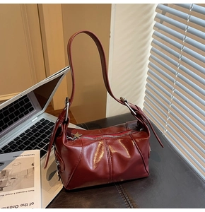 Close-up of glossy burgundy faux leather bag with star-shaped zipper and silver metal buckle