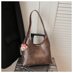 Brown oil wax leather tote bag with a red plaid bow bear charm on a suitcase