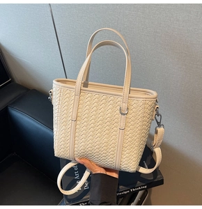 Close-up of cream woven bucket bag with adjustable shoulder strap and silver hardware