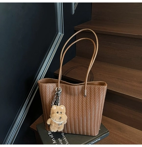 Detail of brown herringbone woven tote bag with cute plush bear and pearl accessory