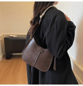 Vue détaillée d'un sac sous le bras vintage marron foncé avec coutures et étiquette en cuir