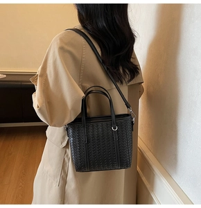 Detailed view of the black woven leather texture and adjustable strap on the tote bag