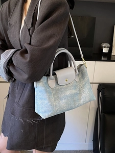 Elegante borsa tote in tela celeste e pelle grigia con tracolla mostrata in una stanza