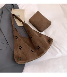 Détail du sac hobo en daim marron avec découpes laser de fleurs et pochette assortie
