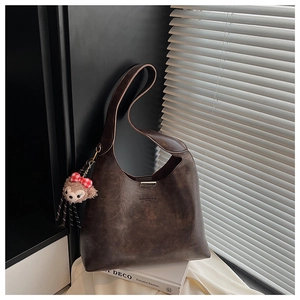 Detail of retro brown leather Hobo bag with plush bear charm and plaid bow accessory