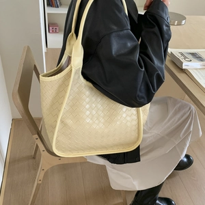 Detail of cream woven leather tote bag with wide weave texture and shoulder strap