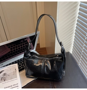 Detail of glossy black shoulder bag with silver star zipper on a leather surface