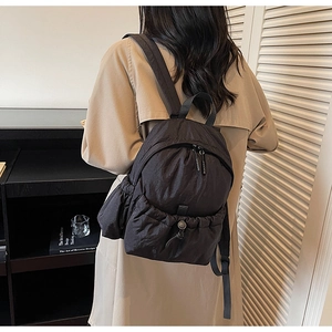 Detail of black nylon backpack featuring drawstring closure and textured ruched design