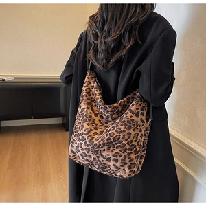 Detail view of large leopard print tote bag worn on shoulder in a modern room setting