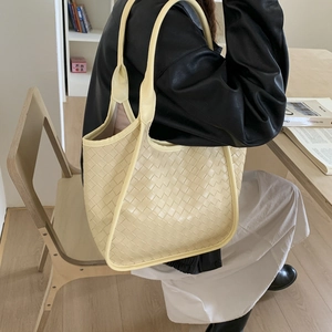 Detailed view of the intricate woven leather texture on a beige minimalist tote bag