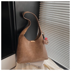 Detail of a brown matte PU leather tote with a gold buckle and cute plush sloth charm