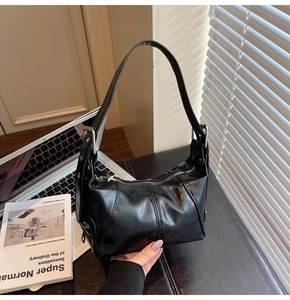 Detail of pleated black leather shoulder bag with star zipper pull on office desk