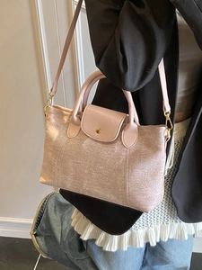 Borsa a tracolla rosa pallido con texture metallica mostrata su una modella