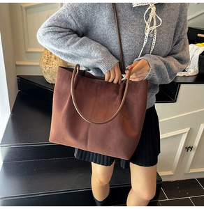 Deep brown suede tote bag featuring vertical stitching shown in an urban lifestyle setting