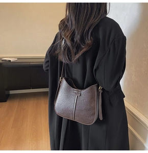 Detail of vintage brown leather handbag featuring wrinkled texture and adjustable gold buckle