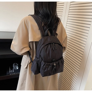 Close-up of lightweight black nylon mini backpack featuring a drawstring front pocket