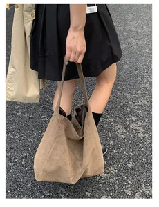 Macro detail of large brown suede tote bag with stylish asymmetrical top handles