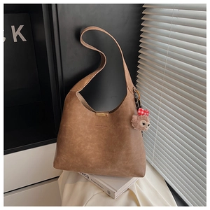 Detail of vintage brown leather bucket bag with top handle and golden clasp closure