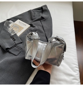 Detail of silver metallic handbag with adjustable leather strap and secure zipper closure