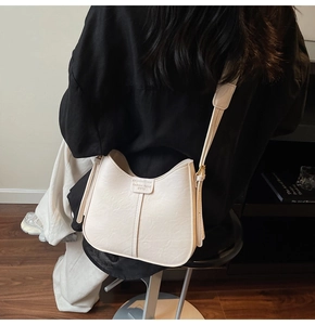 Detail of cream white leather bucket bag showing fine lychee grain and contrast stitching