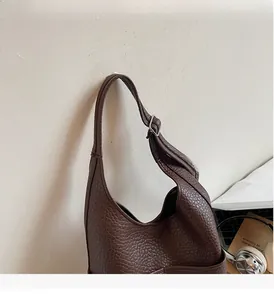 Detail of dark brown pebble leather shoulder bag with adjustable silver buckle and strap