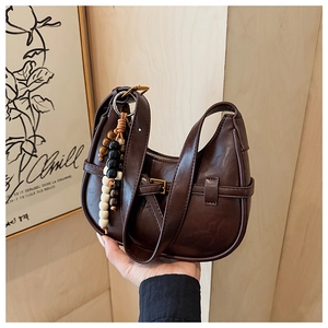 Detail of dark brown hobo bag with vintage buckle and colorful wood bead tassel charm