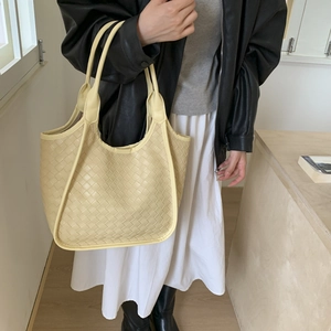Fashionable pale yellow woven leather tote bag shown with a stylish model outfit