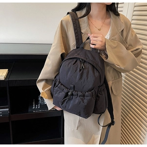 Detail of lightweight black nylon backpack with drawstring pocket shown on a model