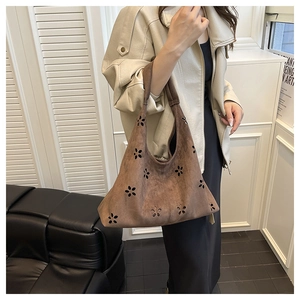 Gros plan du sac hobo en daim marron avec des motifs de fleurs ajourés élégants