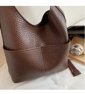 Close-up of brown litchi pattern leather texture and front pocket detail on tote bag