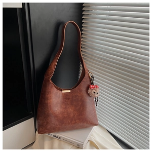 Detail of dark brown leather hobo bag with vintage texture and plush doll charm