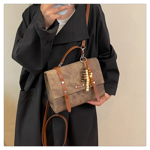 Détail du sac à dos marron vintage avec texture rétro, boucles métal et pendentif perlé