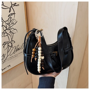 Detail of black leather crescent bag with adjustable buckle and beaded wooden charm